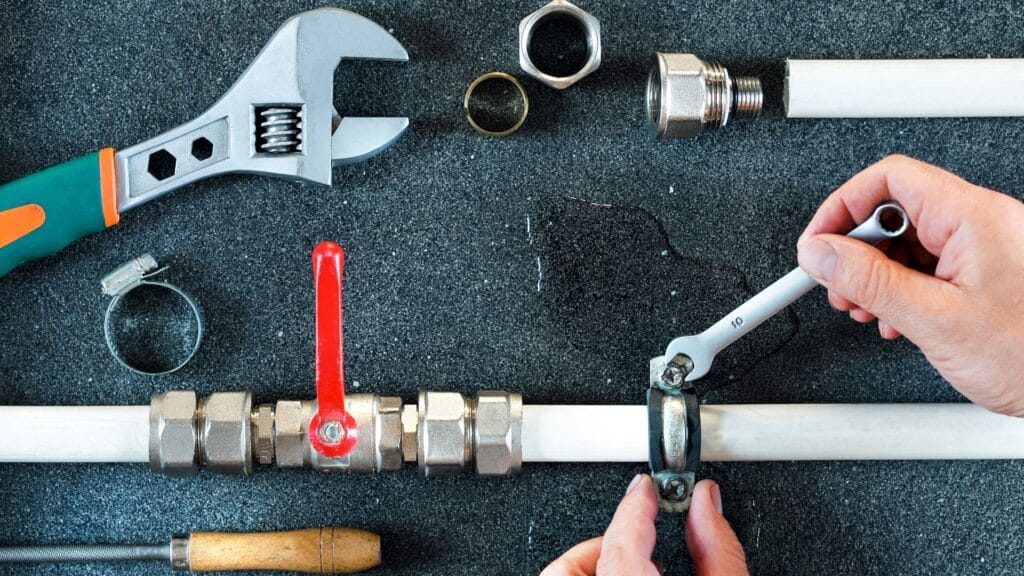 Plumber repairing a pipe valve with an adjustable wrench in Lynn Haven